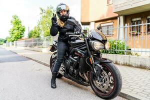 maduro mulher dentro motociclista roupas equitação uma moderno motocicleta ao ar livre foto