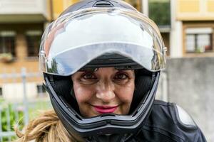 retrato do maduro mulher com motocicleta capacete ao ar livre foto