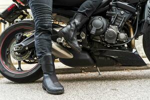 pernas detalhe do maduro mulher dentro motociclista roupas equitação uma moderno motocicleta ao ar livre foto