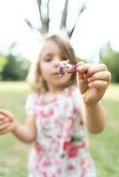 retrato do fofa menina é mostrando uma cabelo grampo dentro uma público parque foto