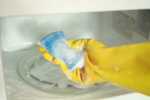 mulher mãos dentro borracha luvas lavando microondas foto