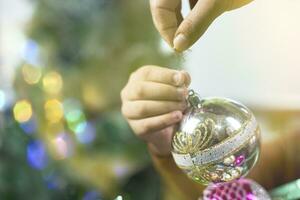 filho ajuda mãe para decorar Natal árvore foto