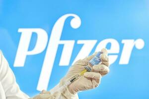 preparando pfizer vacina injeção. uma médico prepara coronavírus vacina para injeção contra pfizer logotipo foto