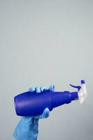 fêmea mão dentro borracha luvas segurando desinfetante spray foto