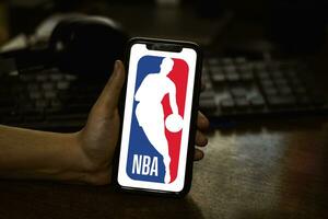 mão aguarde Móvel telefone com nba logotipo foto