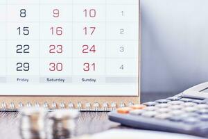 calendário, calculadora e pilha do moedas dentro escritório foto