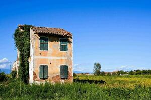 a velho casa dentro a meio do uma campo foto