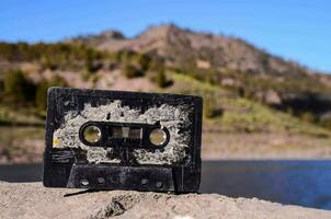 uma cassete fita senta em a terra perto uma lago foto