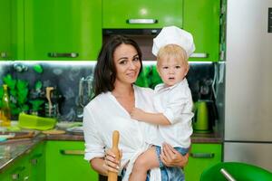 feliz família, mãe segurando dela filho dentro dela braços dentro a cozinha foto