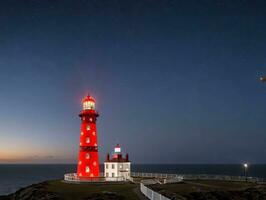 uma vermelho farol às noite. ai gerado foto