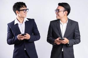 dois empresários asiáticos usando smartphone em fundo branco foto