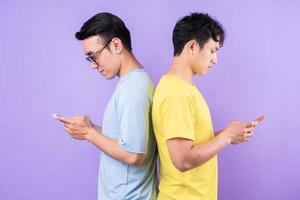 dois irmãos asiáticos usando telefones celulares em fundo roxo foto