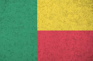 bandeira do benin retratada em cores brilhantes de tinta na parede de reboco em relevo antigo. banner texturizado em fundo áspero foto