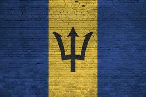 barbados bandeira retratado dentro pintura cores em velho tijolo muro. texturizado bandeira em grande tijolo parede alvenaria fundo foto