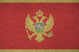 bandeira de montenegro retratada em cores de tinta brilhante na parede de reboco em relevo antigo. banner texturizado em fundo áspero foto
