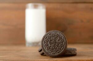 muitos Oreo sanduíche creme biscoitos e leite vidro em de madeira fundo foto