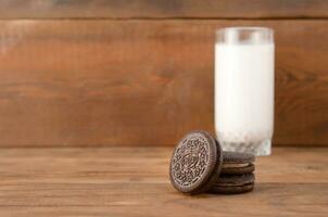 muitos Oreo sanduíche creme biscoitos e leite vidro em de madeira fundo foto