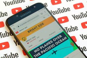 brilhante lado oficial Youtube canal em Smartphone tela em papel Youtube fundo. foto