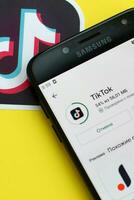 tiktok inscrição dentro playmarket em samsung Smartphone tela em amarelo fundo. tiktok é uma popular compartilhamento de vídeo social trabalho em rede serviço possuído de bytedance foto