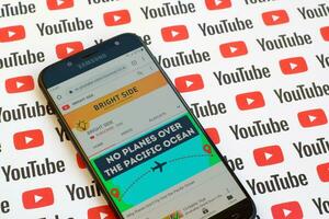 brilhante lado oficial Youtube canal em Smartphone tela em papel Youtube fundo. foto