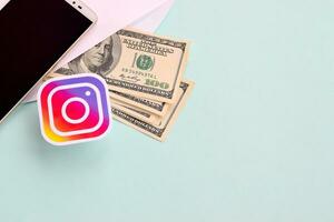 Instagram papel logotipo mentiras com envelope cheio do dólar contas e Smartphone foto