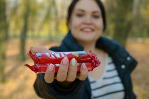 Carcóvia, Ucrânia - Outubro 21, 2019 jovem menina passes uma kit Kat chocolate Barra dentro a outono parque. a manifestação do gentileza, tratando com doces foto