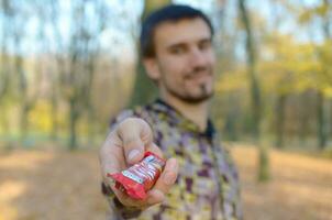 Carcóvia, Ucrânia - Outubro 21, 2019 jovem homem passes uma kit Kat chocolate Barra dentro a outono parque. a manifestação do gentileza, tratando com doces foto