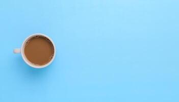 mão segurando uma caneca de café em um fundo azul foto