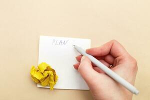 mulher mão escrevendo uma plano ou para Faz Lista em peça do papel para notas com uma amassado yelllow papel foto