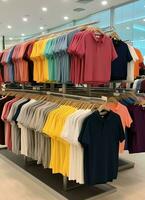 linha do elegante pólo Camisetas para homem em de madeira cabide ou prateleira dentro uma roupas boutique varejo fazer compras conceito de ai gerado foto