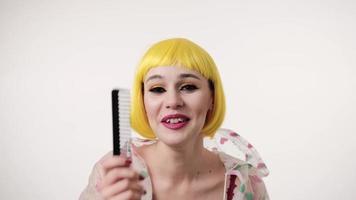 closeup retrato de mulher com maquiagem colorida em estilo futurista, vestindo peruca amarela e sorrindo sobre fundo claro. olhar criativo de mulher foto