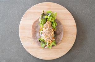 embrulhe o rolo de salada com salada de atum e milho no prato de madeira foto