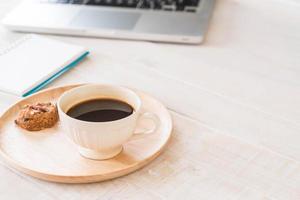 café preto e biscoitos com laptop e notebook na mesa foto
