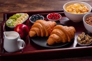 delicioso café da manhã com croissants frescos e frutas vermelhas maduras foto