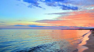 uma verão pôr do sol cenário em a horizonte. mar dentro dourado cores e surpreendente nuvens em céu. foto