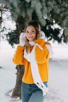 adolescente Loiras dentro uma amarelo suéter lado de fora dentro inverno. uma Adolescência menina em uma andar dentro inverno roupas dentro uma Nevado floresta foto