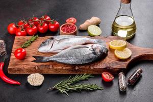 Peixe dourado cru com temperos cozinhando na tábua foto