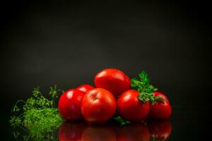 maduro vermelho tomates com verduras em Preto fundo. foto