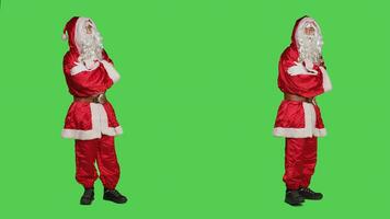 homem vestido Como santa sentindo-me impaciente, esperando para alguma coisa enquanto ele carrinhos sobre cheio corpo tela verde pano de fundo. santo usuario personagem ritmo por aí a estúdio, Natal véspera feriado. foto