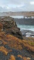 fantástico gullfoss cascata dentro Islândia com maciço rio fluindo fora montanha borda, norte região selvagem natureza. islandês cenário com neve coberto Campos e água corrente corrida baixa falésias. foto