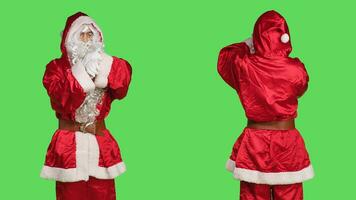 impaciente santa claus dentro terno verificação Tempo em relógio de pulso enquanto ele carrinhos sobre tela verde pano de fundo. jovem adulto vestido dentro festivo inverno personagem traje esperando para algo, natal espírito. foto