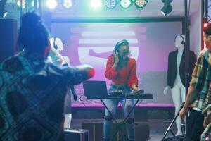 mulher músico usando dj controlador enquanto realizando em etapa dentro Boate. africano americano disco brincalhão jogando e mistura eletrônico música durante show discoteca festa dentro clube foto