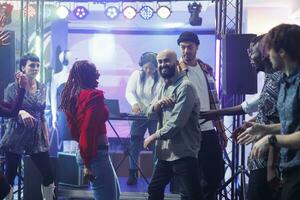 alegre diverso casal rindo enquanto improvisando dança batalha às Boate discoteca. feliz despreocupado pessoas mostrando movimentos em lotado pista de dança e tendo Diversão enquanto balada às noite foto