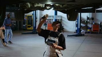 qualificado engenheiro por baixo suspenso carro dentro reparar comprar, usando trabalhos luz para Verifica para danos durante manutenção. especialista usando profissional ferramenta e tábua para examinar veículo em a sobrecarga lift foto