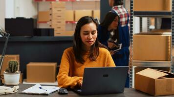 mulher empreendedor verificação estoque Produção em pc, usando computador portátil para trabalhos em fornecem cadeia ordem gerenciamento. jovem adulto planejamento envio para pequeno o negócio desenvolvimento. portátil tomada. foto