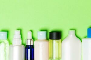 vista superior de frascos de cosméticos em fundo verde. conceito de cuidados com a pele com espaço para seu design foto