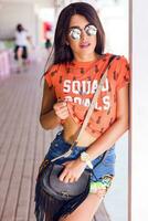 ao ar livre verão moda retrato do jovem grandes cabelo morena posando dentro de praia bar. foto