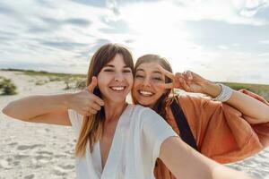 dois mulheres sorridente e posando para a Câmera em a de praia foto