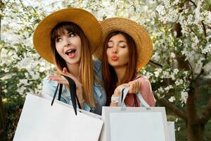 dois mulheres com compras bolsas dentro frente do uma árvore foto