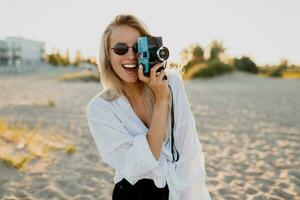 à moda menina com retro Câmera em ensolarado de praia. verão período de férias. liberdade e viagem conceito. foto